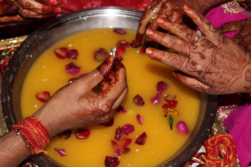 Hands over a bowl of turmeric water at a haldi ceremony